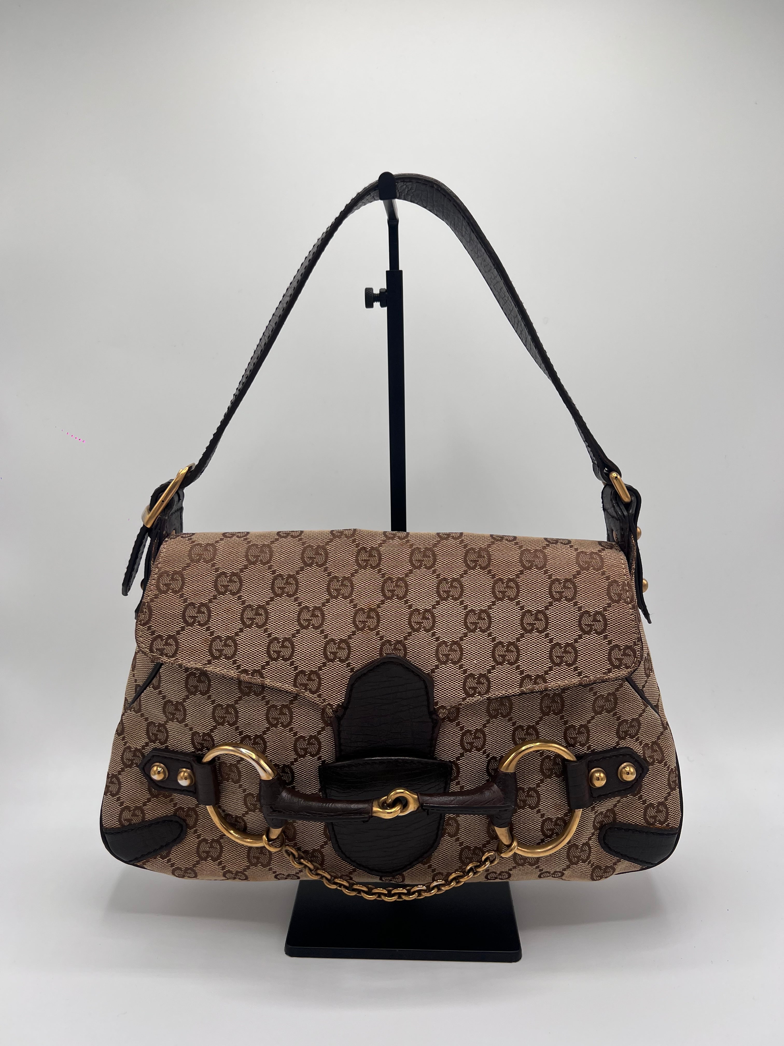 Vintage Gucci designer handbag with patterned fabric and gold hardware on a white background