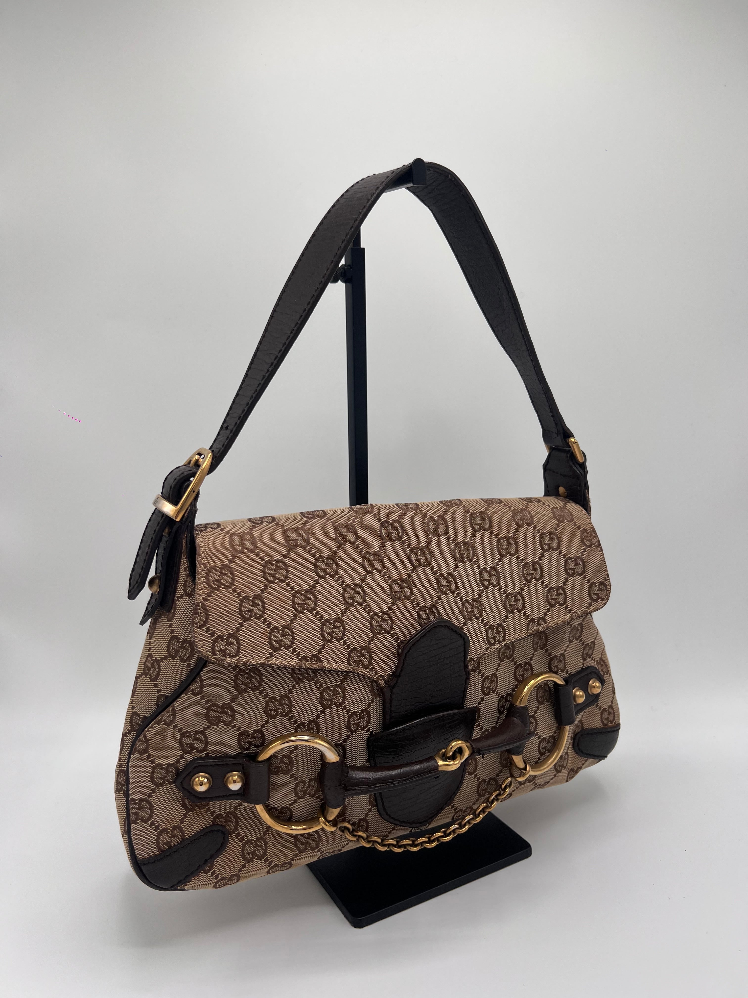 Brown patterned handbag with black accents on a light gray background