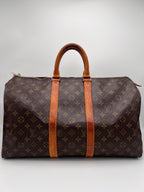 LOUIS VUITTON KEEPALL 45. Designer handbag with monogram pattern on a light gray background