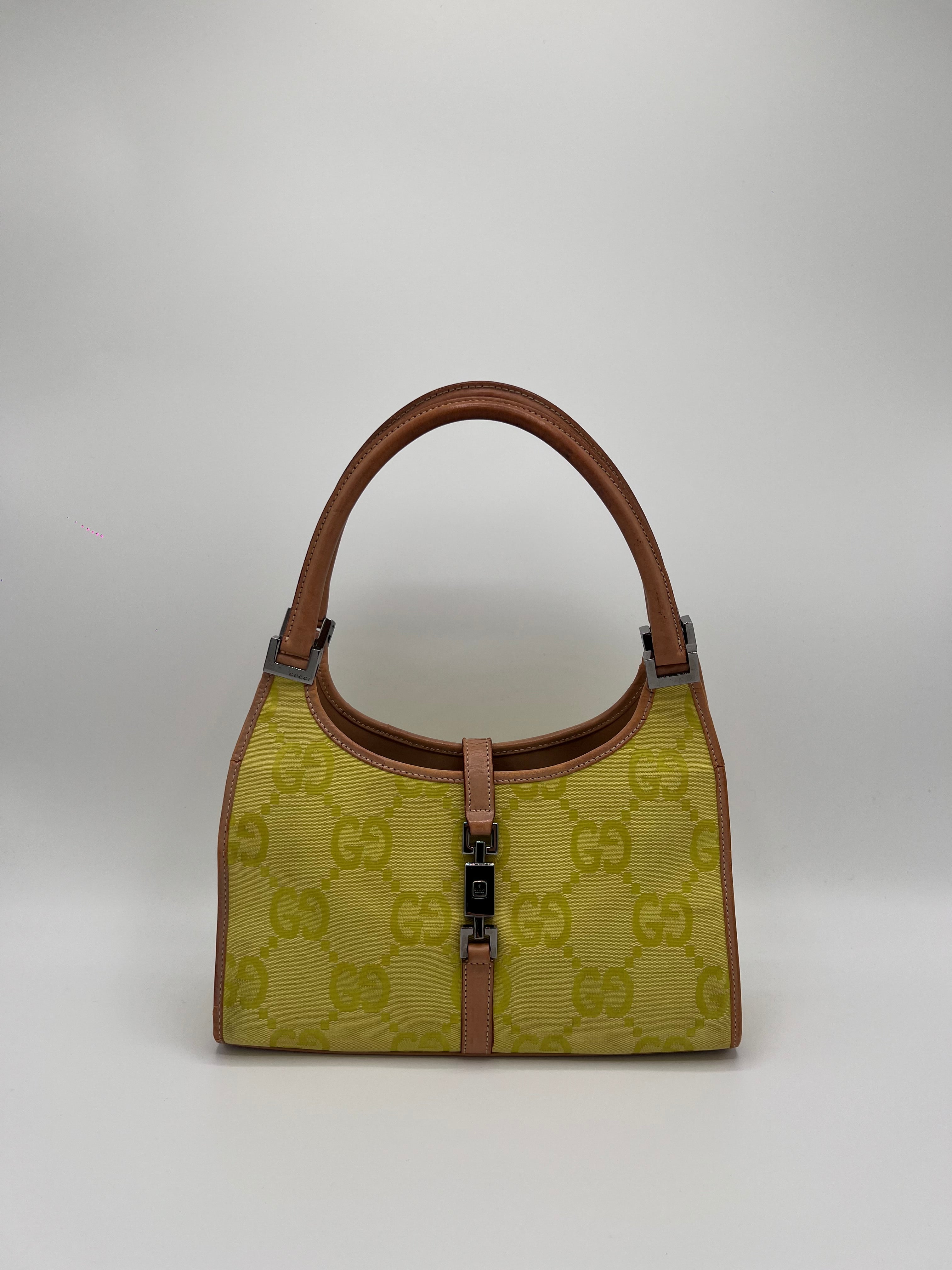 Yellow Gucci Handbag with brown handle and patterned body on a white background